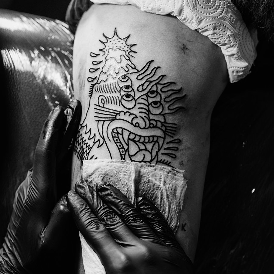 partial-view-of-tattoo-artist-in-gloves-working-on-2XXE5F4.jpg